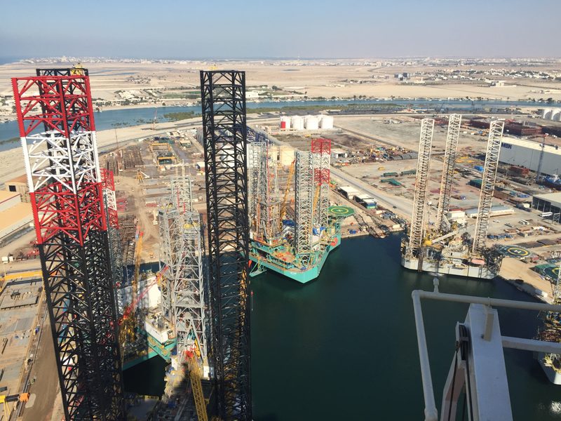 Multiple jack-up rigs and construction activity viewed from an elevated position